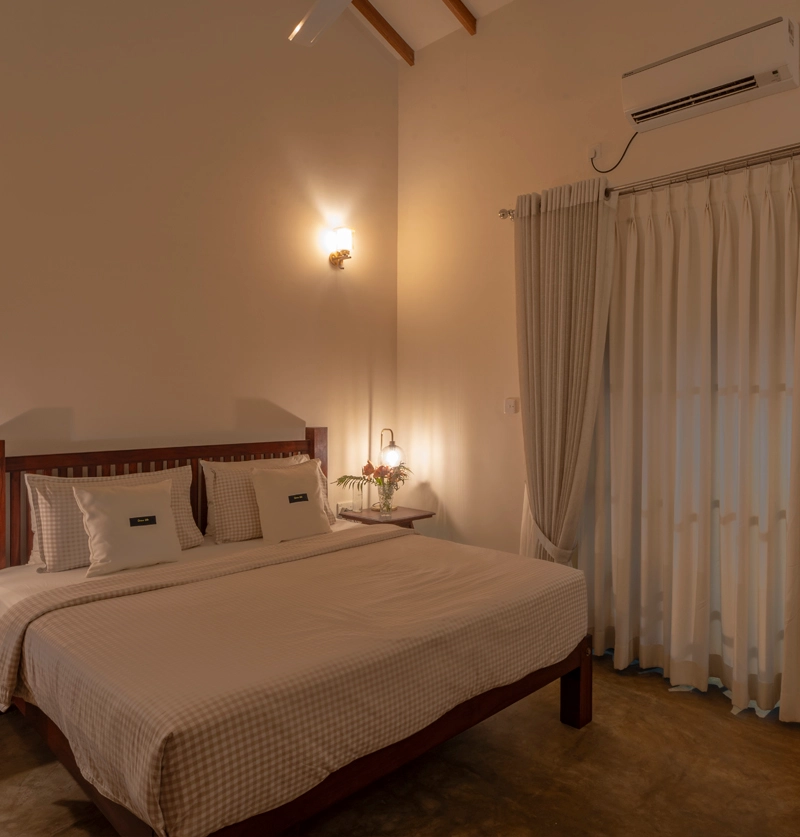 Spacious king-size bedroom with air conditioning, warm lighting, and elegant curtains at Sevena Villa Sri Lanka