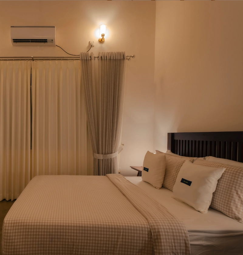 Modern villa bedroom with king-size bed, calming lighting, and floor-to-ceiling curtains at Sevena Villa